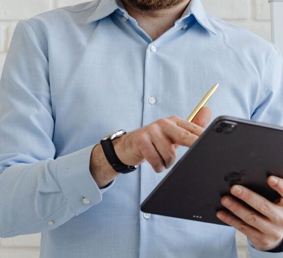 Mand iført blå skjorte og en ipad i hånden
