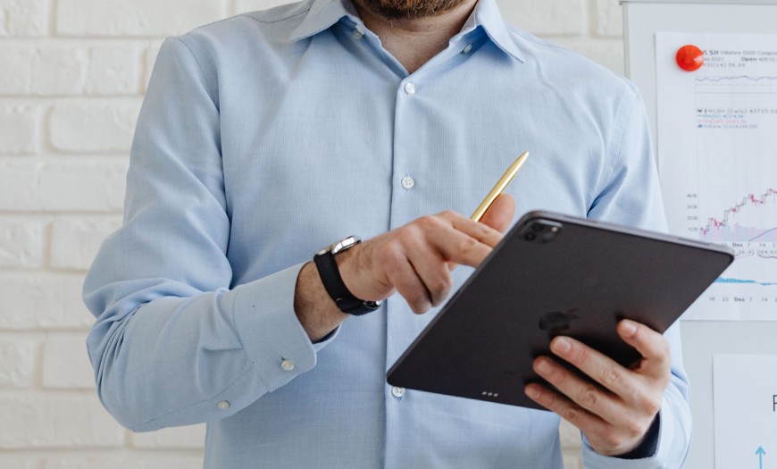 Mand iført blå skjorte og en ipad i hånden