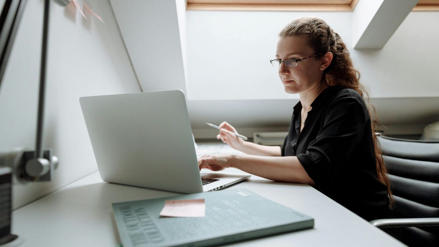 Kvinder der sidder ved skrivebord bag laptop