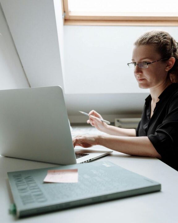 Kvinder der sidder ved skrivebord bag laptop